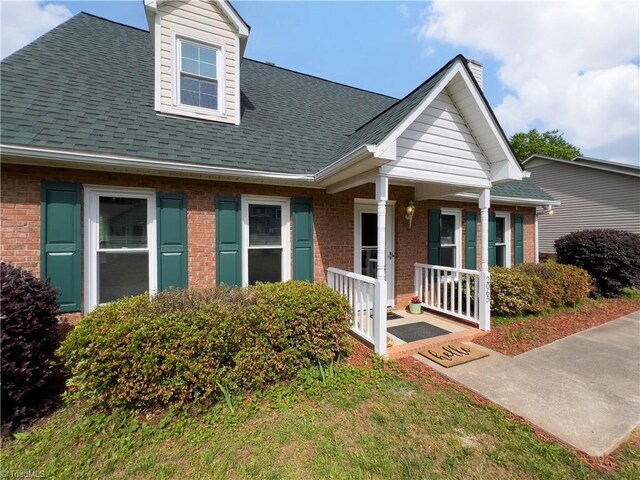 2065 Ardmore Village Ln, Winston-Salem, NC 27127 - view of front of home featuring brick siding, a porch, a chimney, and roof with shingles