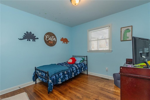 bedroom featuring visible vents, baseboards, and wood finished floors