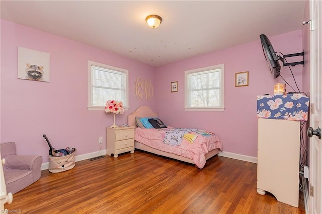 bedroom featuring multiple windows, wood finished floors, and baseboards