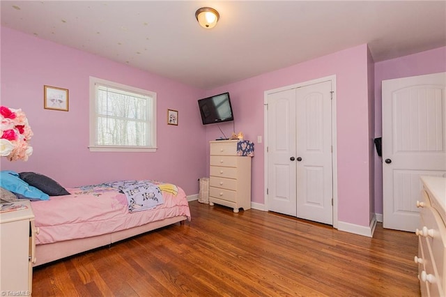 bedroom with a closet, baseboards, and wood finished floors