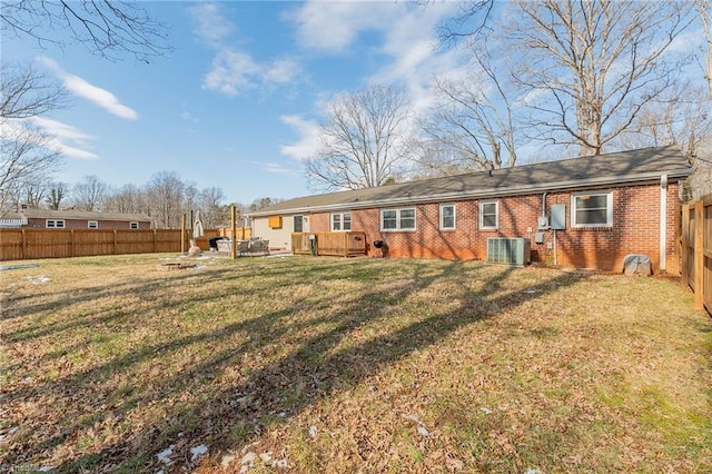 rear view of house featuring a yard, cooling unit, brick siding, and a fenced backyard