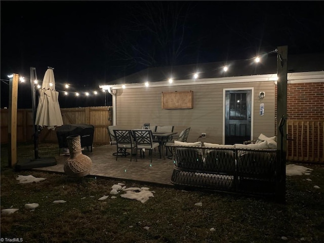 back of house at twilight with a patio area, an outdoor hangout area, and fence