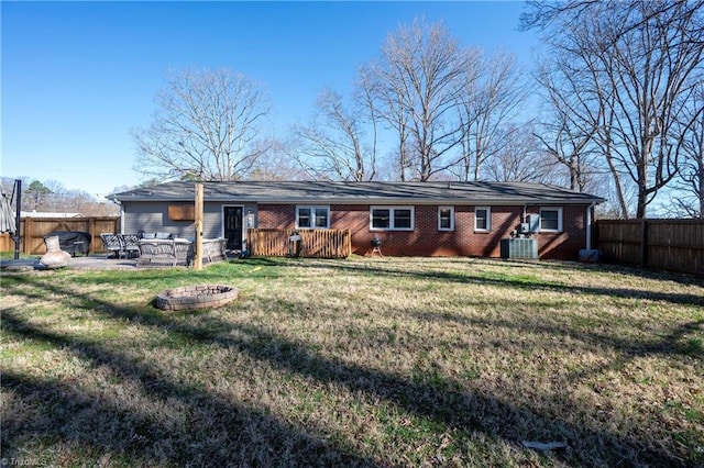 rear view of property with a patio, a yard, a fenced backyard, a fire pit, and brick siding