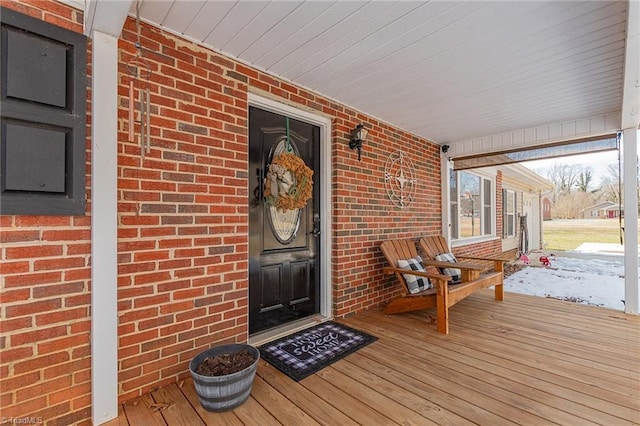 doorway to property with brick siding and covered porch