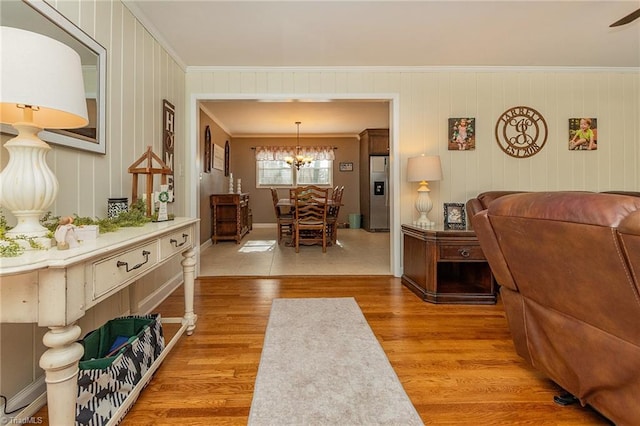 living room featuring crown molding, light wood-style floors, and a chandelier