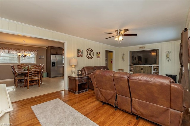 living room featuring crown molding, ceiling fan with notable chandelier, and light wood finished floors