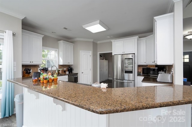 126 Strand Dr, New London, NC 28127 - kitchen featuring appliances with stainless steel finishes, a peninsula, crown molding, decorative backsplash, and dark stone countertops