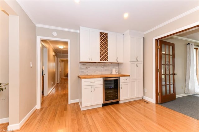 bar featuring white cabinets, ornamental molding, wooden counters, and beverage cooler