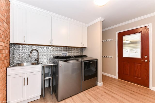 laundry area with sink, crown molding, washer and clothes dryer, cabinets, and light wood-type flooring