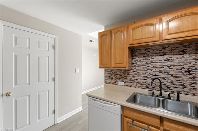 kitchen featuring dishwasher, a sink, visible vents, and decorative backsplash