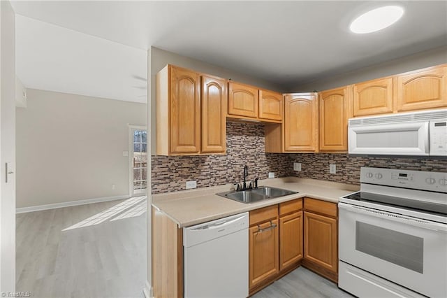 kitchen with light wood finished floors, light countertops, backsplash, a sink, and white appliances