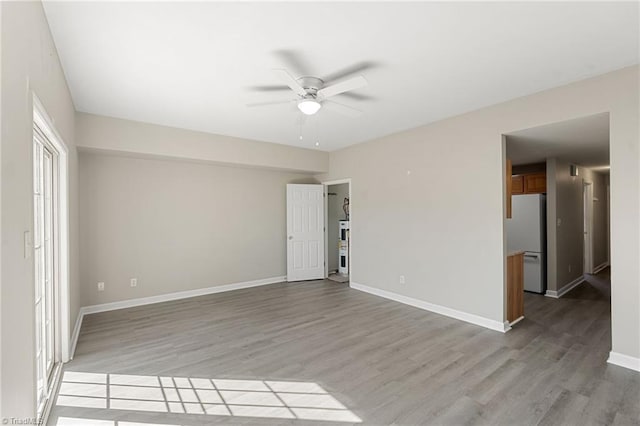 spare room featuring light wood-style floors, ceiling fan, and baseboards