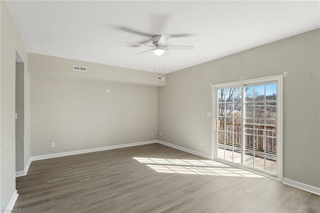 empty room featuring wood finished floors, visible vents, and baseboards