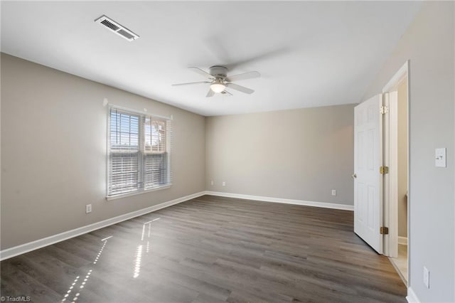 spare room with baseboards, visible vents, a ceiling fan, and wood finished floors