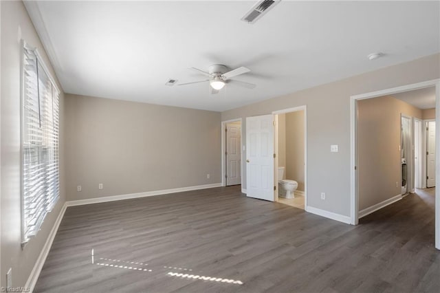 unfurnished bedroom featuring baseboards, visible vents, a ceiling fan, ensuite bath, and wood finished floors