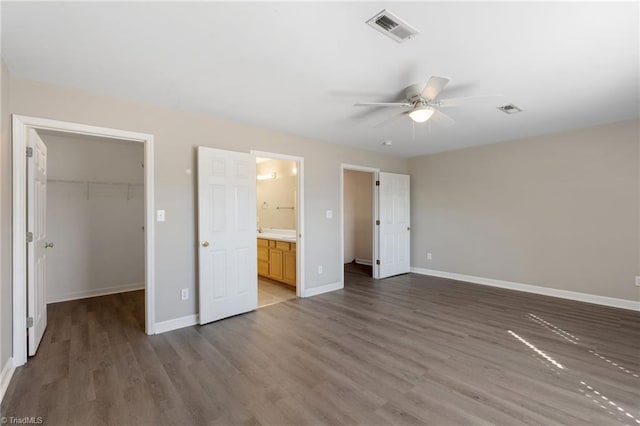 unfurnished bedroom featuring baseboards, a spacious closet, visible vents, and wood finished floors