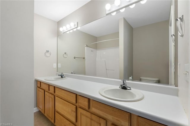 bathroom featuring double vanity, tile patterned flooring, a sink, and toilet