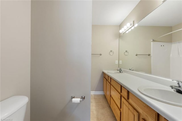 bathroom featuring tile patterned floors, a sink, toilet, and double vanity