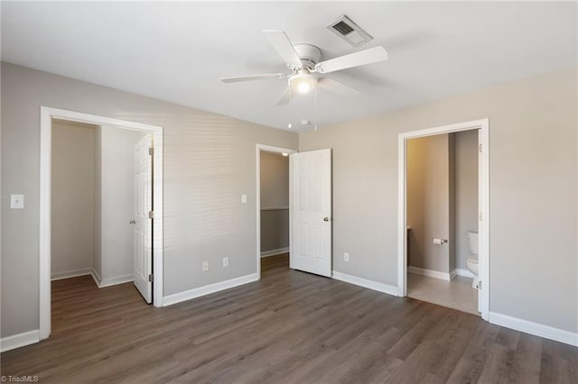 unfurnished bedroom with wood finished floors, a ceiling fan, visible vents, baseboards, and ensuite bath