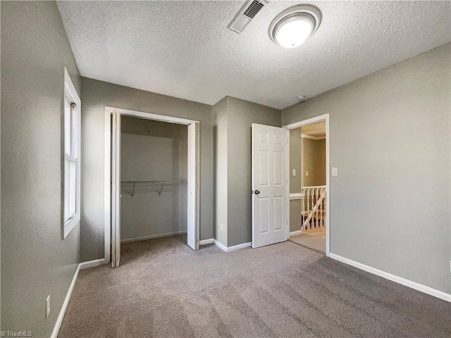 unfurnished bedroom featuring light colored carpet, a closet, and a textured ceiling