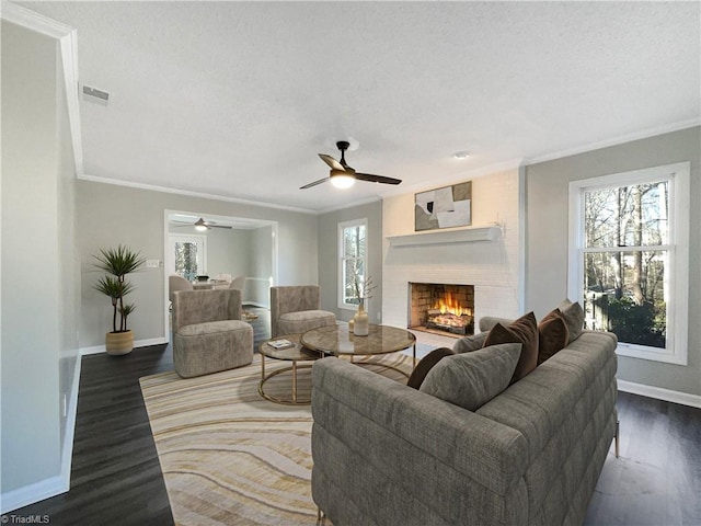 living room with plenty of natural light, a brick fireplace, ceiling fan, and dark hardwood / wood-style flooring