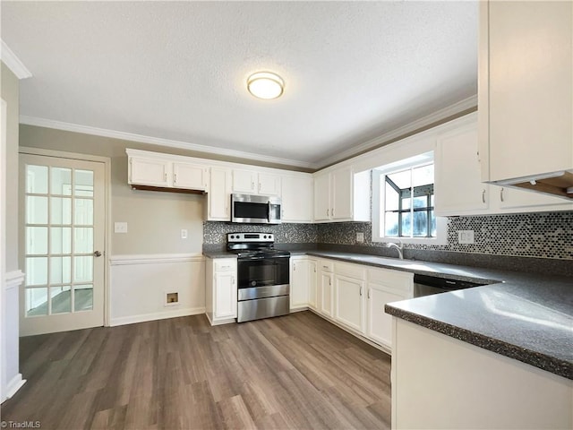 kitchen with stainless steel appliances, white cabinetry, and dark wood-type flooring