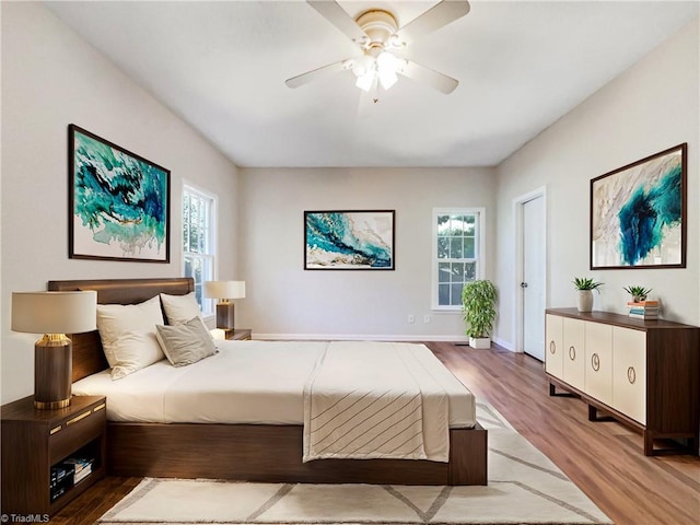 bedroom with ceiling fan, wood-type flooring, and multiple windows