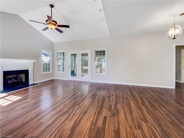 unfurnished living room with ceiling fan with notable chandelier, high vaulted ceiling, and dark hardwood / wood-style flooring