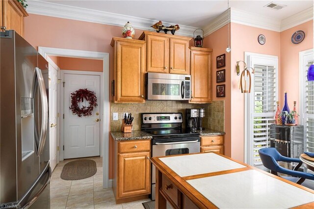 129 Turnbuckle Ct, Clemmons, NC 27012 - kitchen with stainless steel appliances, decorative backsplash, crown molding, light tile patterned floors, and brown cabinetry
