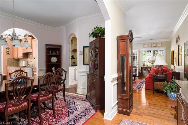 129 Turnbuckle Ct, Clemmons, NC 27012 - dining area with light wood-style flooring, a chandelier, arched walkways, and crown molding