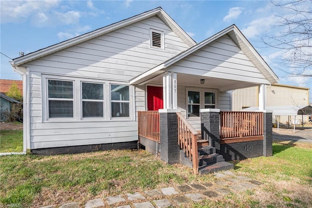 back of house featuring covered porch and a yard