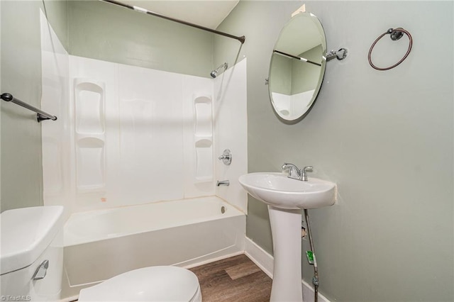 bathroom with hardwood / wood-style floors, shower / bathtub combination, and toilet