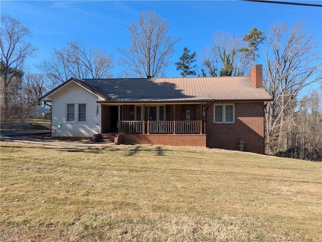 ranch-style home featuring a chimney, metal roof, covered porch, a front lawn, and brick siding