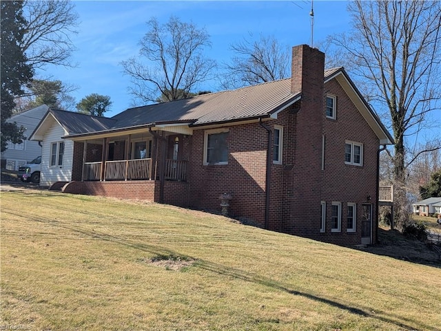 rear view of house with a chimney, a lawn, and brick siding