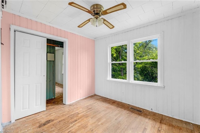 1198 Red Bank Rd, Germanton, NC 27019 - unfurnished bedroom featuring light wood-style floors, ornamental molding, wood walls, and a ceiling fan