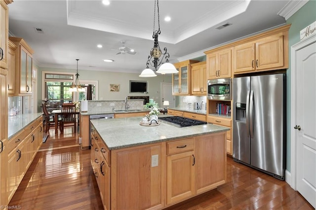 kitchen featuring ceiling fan with notable chandelier, light stone countertops, stainless steel appliances, dark hardwood / wood-style flooring, and a kitchen island