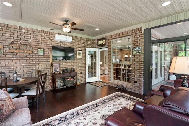 living room with dark hardwood / wood-style flooring, an AC wall unit, brick wall, and ceiling fan