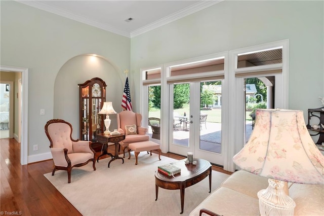 living room featuring a towering ceiling, hardwood / wood-style floors, crown molding, and french doors