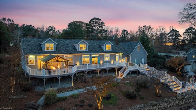 back house at dusk featuring a wooden deck