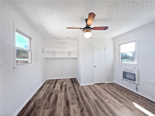 unfurnished bedroom featuring heating unit, wood finished floors, baseboards, ceiling fan, and a textured ceiling