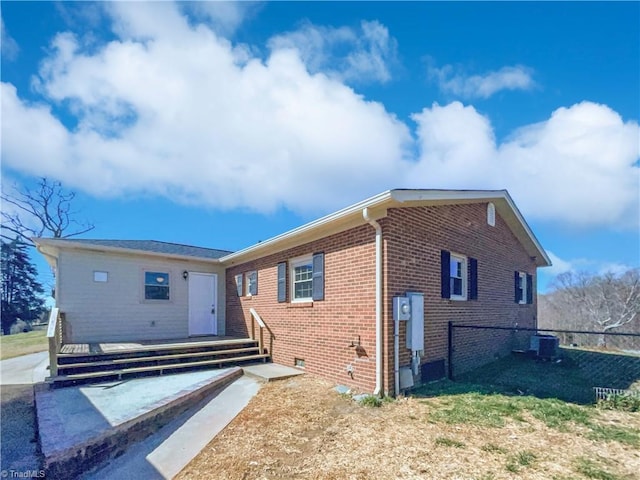 back of house featuring brick siding, crawl space, central AC, and fence