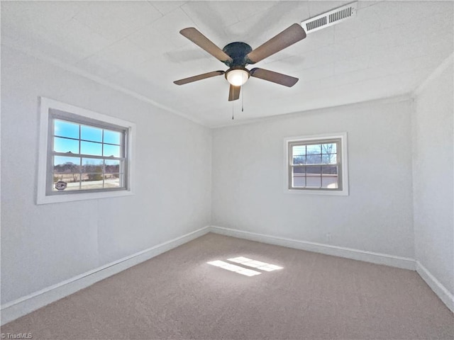 carpeted spare room with visible vents, baseboards, and a ceiling fan