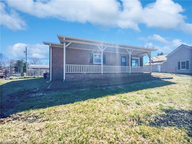 view of front of house with a front yard, fence, brick siding, and covered porch