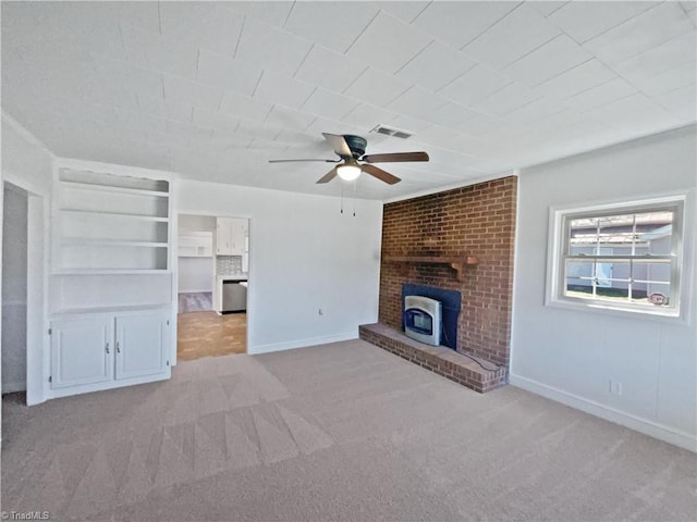 unfurnished living room with visible vents, baseboards, carpet, a wood stove, and a ceiling fan