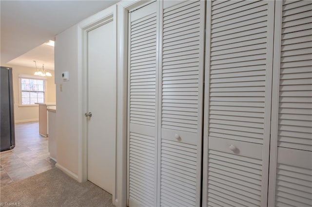 interior space with stainless steel refrigerator, carpet flooring, and a chandelier