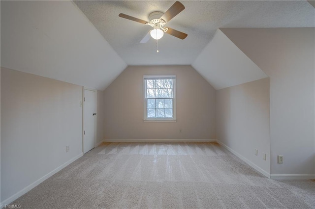 bonus room featuring lofted ceiling, ceiling fan, light colored carpet, and a textured ceiling