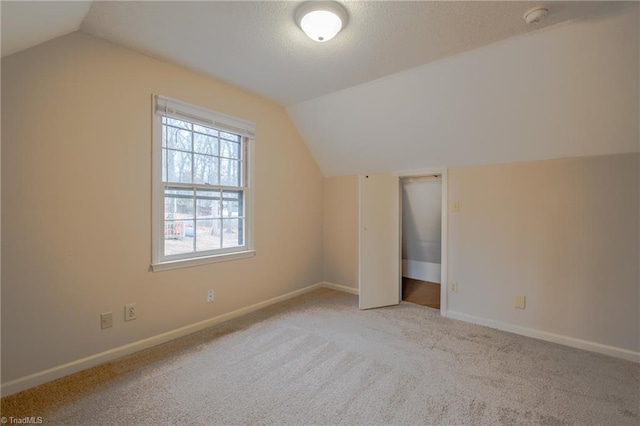 bonus room featuring baseboards, lofted ceiling, carpet, and a textured ceiling