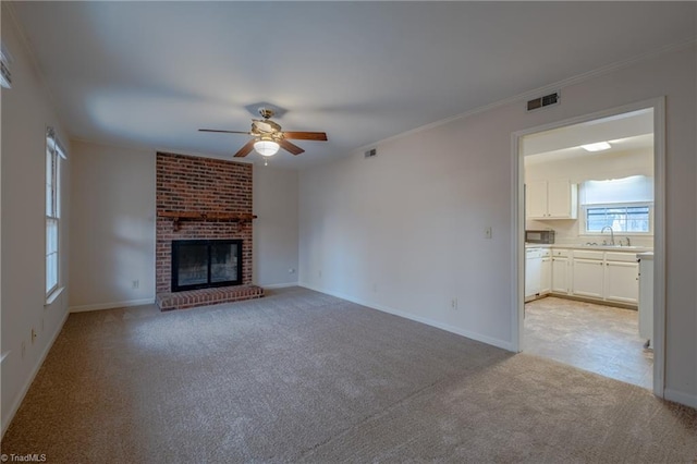 unfurnished living room with a brick fireplace, sink, light carpet, and ceiling fan