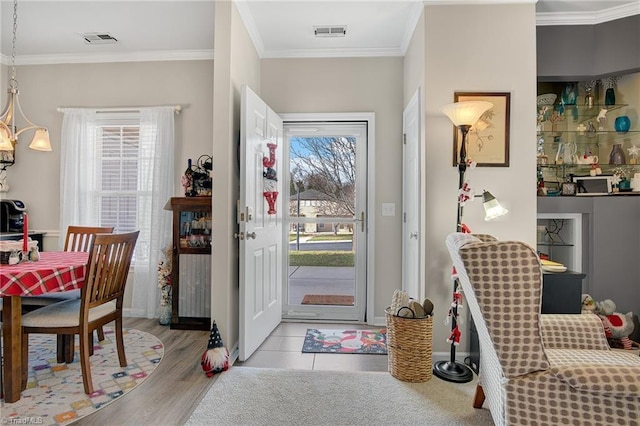 entryway featuring light hardwood / wood-style floors, a healthy amount of sunlight, and ornamental molding