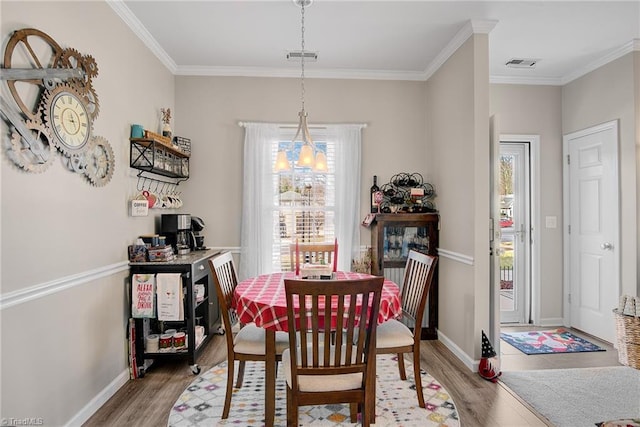 dining room with light wood-type flooring and crown molding